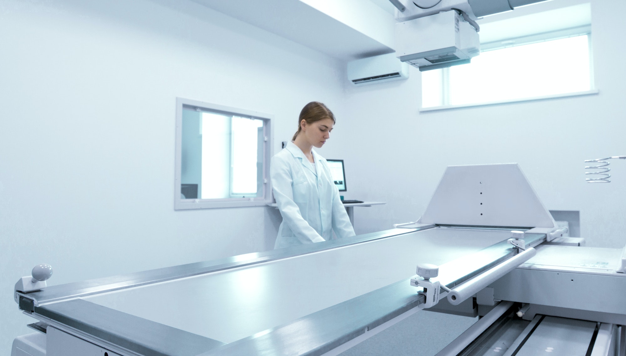 Woman doctor preparing X-ray equipment for making roentgenogram